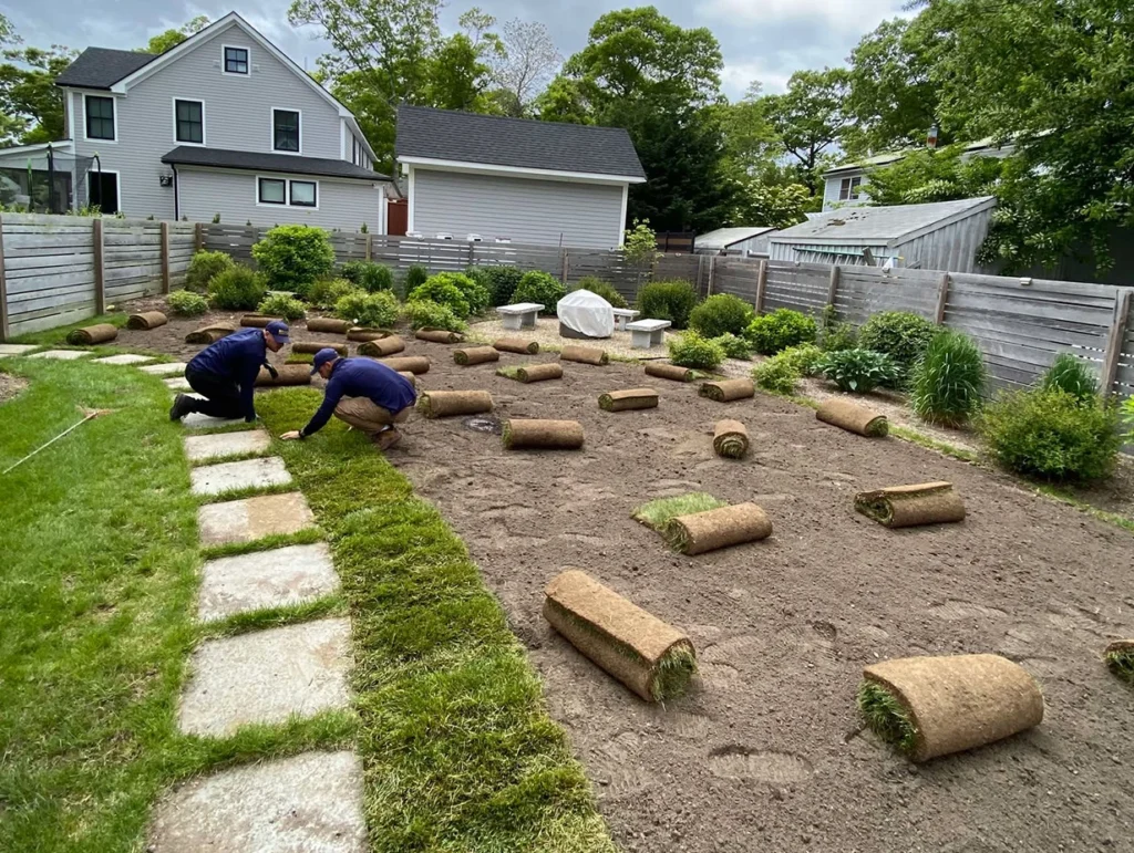 SOD lawn installing in the process on Martha's Vineyard property. Service provided by Estate Care, 2 visible workers in the photo